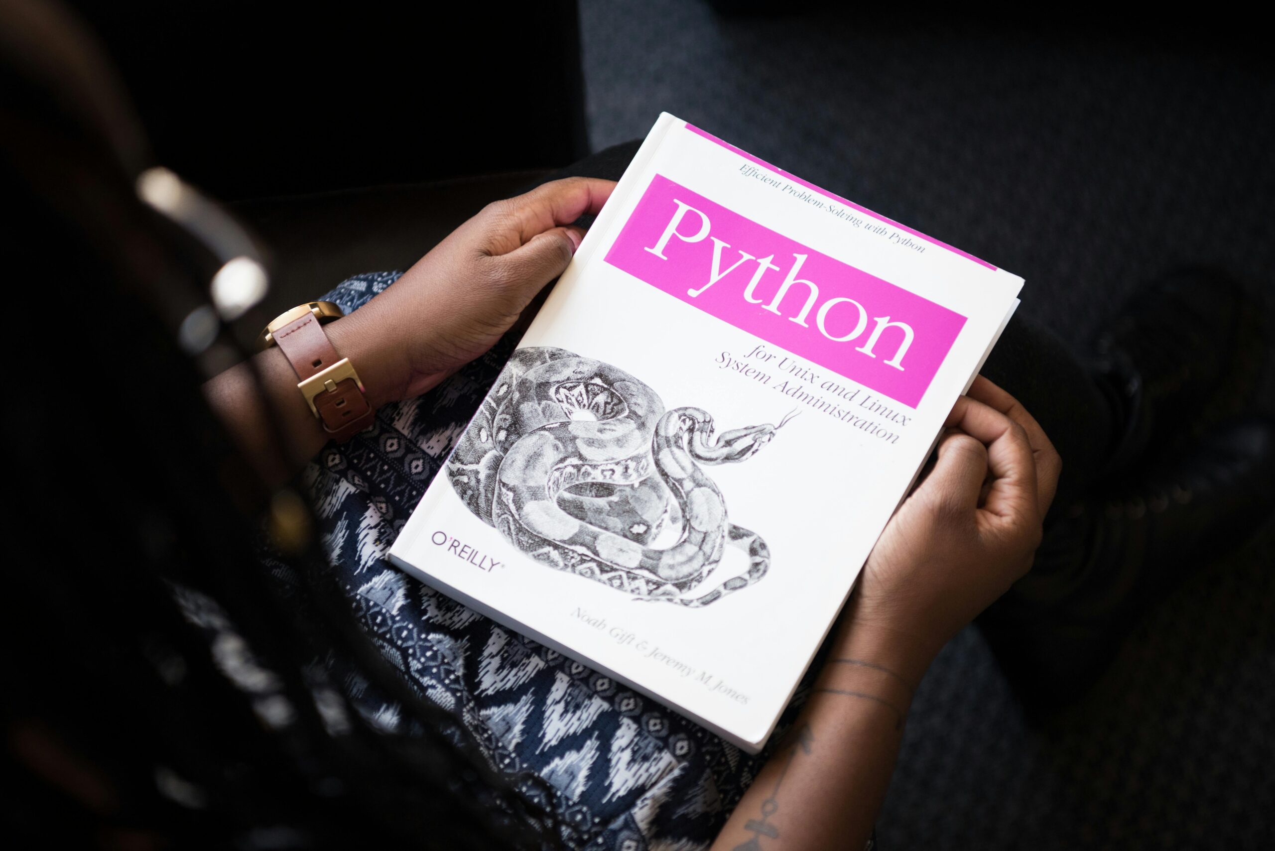 Person holding a Python programming book for Python Course in Chandigarh by CADD Primer, focused on practical learning and career growth